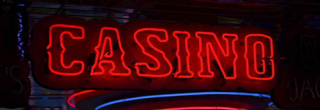 Neon lights display the word 'CASINO' in bright red, standing out against a dark background. The vibrant glow reflects a lively and bustling atmosphere.
